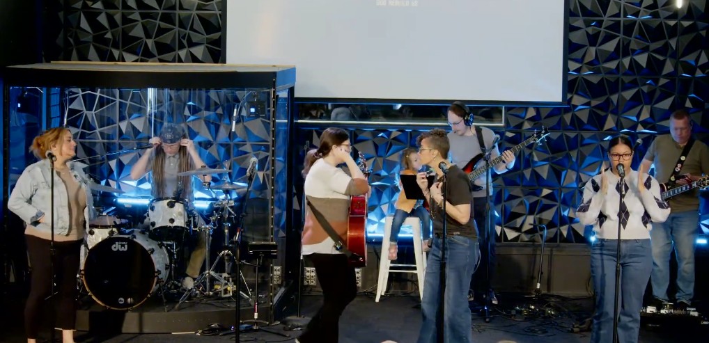 Full worship band — drums, guitar, and vocals — in motion
